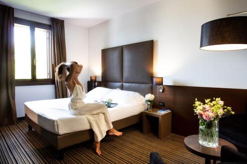 a woman sitting on a bed in a hotel room at Sweet Hotel in Longa