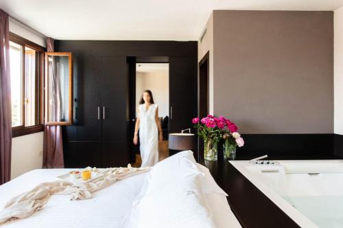 a woman in a white dress standing in a bedroom at Sweet Hotel in Longa
