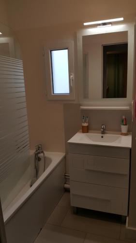 a bathroom with a sink and a tub and a mirror at Appartement à deux pas de l ocean in Moliets-et-Maa