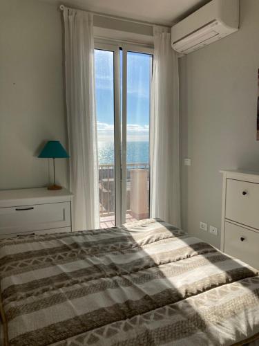 a bedroom with a bed and a large window at Rosso Tramonto luxury-white- LADISPOLI, Lungomare Regina Elena 58 in Ladispoli