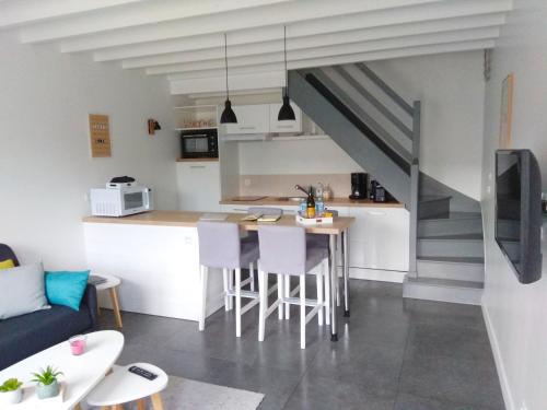 a kitchen and living room with a table and a staircase at Maison Cosy entre CAP FREHEL et SAINT MALO 1km PLAGE 5min GR34 Wifi Jardin Vélos "CASA OHANA" in Saint-Cast-le-Guildo