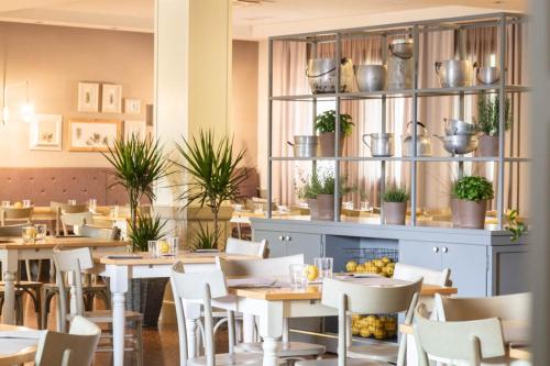a restaurant with tables and chairs and plants at Sweet Hotel in Longa