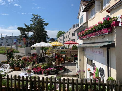 a building with flowers and tables and umbrellas at House of Harmony in Stäfa
