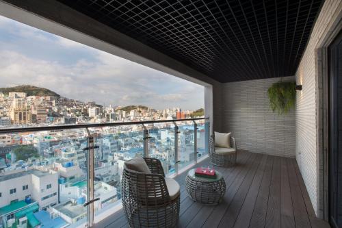 a balcony with chairs and a view of a city at Nampo Hound Hotel Premier in Busan