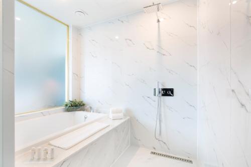 a white bathroom with a tub and a window at Nampo Hound Hotel Premier in Busan