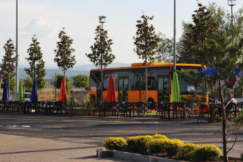 an orange bus with tables and chairs and umbrellas at Best Western Hotel Galla in Pristina