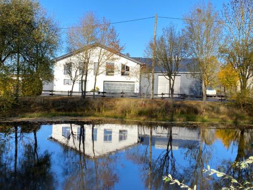 a white house with a pond in front of it at Ferienwohnungen Eifelausblick in Hümmel