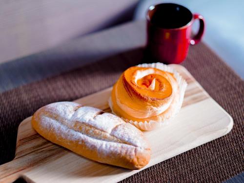 two pastries on a cutting board with a cup of coffee at Hotel AreaOne Takamatsu in Takamatsu