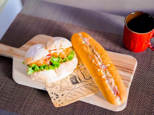 a sandwich and a hot dog on a plate with a cup of coffee at Hotel AreaOne Takamatsu in Takamatsu