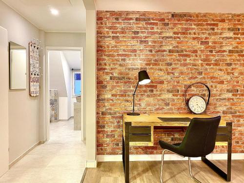 een bakstenen muur in een kamer met een bureau en een stoel bij Schöne Ferienwohnungen teilweise mit Dachterrasse im Herzen von Itzehoe in Itzehoe
