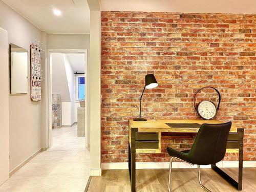 pared de ladrillo en una habitación con escritorio y silla en Schöne Ferienwohnungen teilweise mit Dachterrasse im Herzen von Itzehoe en Itzehoe