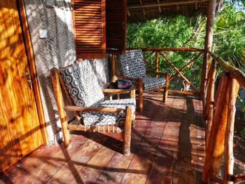 a porch with two chairs and a table at COCO REEF ECOLODGE in Kizimkazi