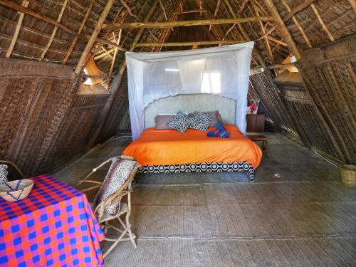 a bedroom with a bed in a thatched room at COCO REEF ECOLODGE in Kizimkazi