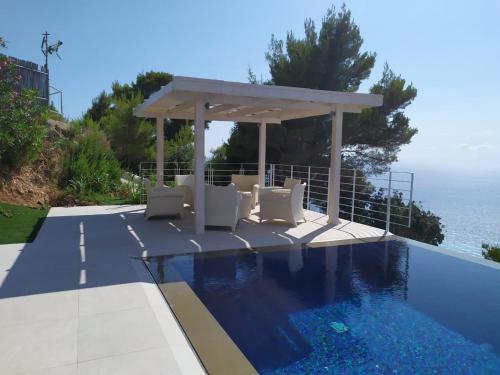 een zwembad met een prieel naast de oceaan bij Okeanos Luxury Villas - Resort in Athanion