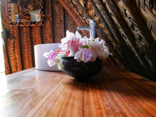 a black vase filled with flowers on a wooden table at COCO REEF ECOLODGE in Kizimkazi