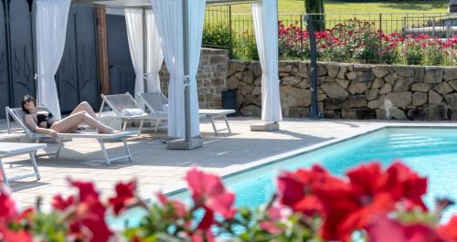 a woman sitting on a chair in front of a pool at Il Contado Country House & Spa in Poppi