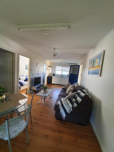 a living room filled with furniture and a table at Park Beach Cabins in Coffs Harbour