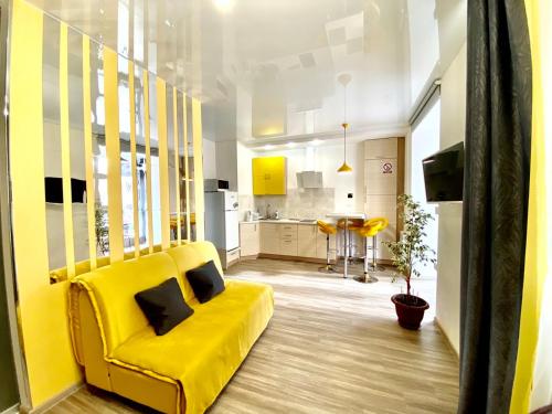 een gele bank in een woonkamer met een keuken bij Grey&Yellow на Коцюбинського in Vinnytsya