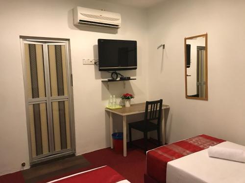 um quarto com uma secretária, uma televisão e uma cama em HL HOTEL Kota Bharu em Kota Bharu
