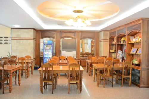 uma sala de jantar cheia de mesas e cadeiras de madeira em Submukda Phoomplace Hotel em Mukdahan