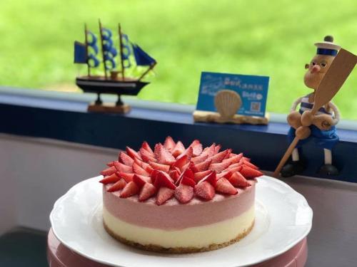 a cake with strawberries on a plate next to a window at Blue and White Style Holiday B&B in Guanshan