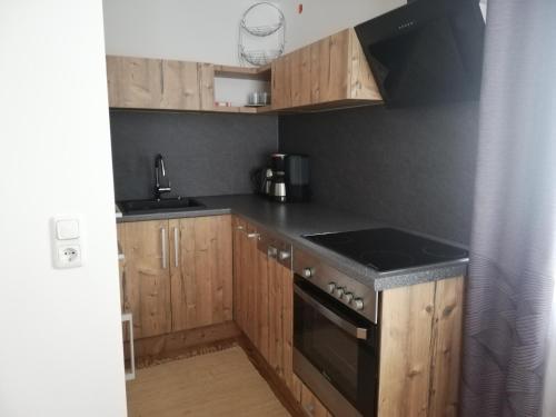 a kitchen with wooden cabinets and a black stove top oven at Ferienwohnung mit Aussicht auf die Burg in Wertheim