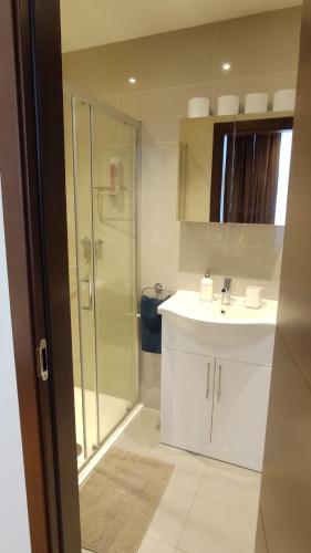 uma casa de banho com uma cabina de duche em vidro e um lavatório. em The Kilburn Arms em Londres
