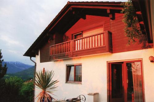 ein rotes und weißes Haus mit einem Balkon in der Unterkunft Ferienwohnung Greimelberg in Frasdorf