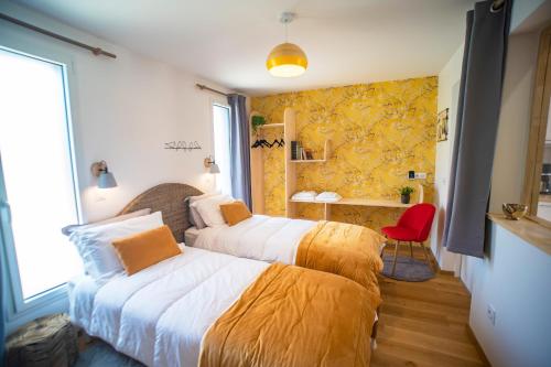 a bedroom with two beds and a red chair at Le jardin des 4 saisons in Le Mans