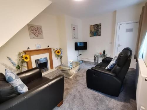 a living room with two leather chairs and a fireplace at Gwynedd House Flat 3 in Pentraeth