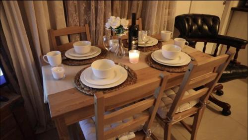 una mesa de madera con platos y tazas y una botella de vino en Private Garden House, en Haifa