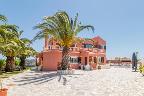 a pink house with palm trees in front of it at Villa Paradis Pêra - Quartos para férias in Pêra