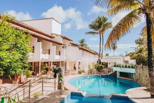 a villa with a swimming pool and palm trees at Poty Praia Hotel in Porto Seguro