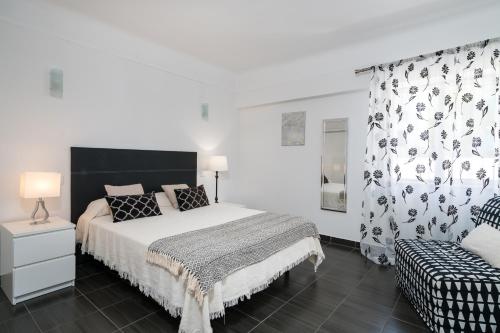 een witte slaapkamer met een bed en een stoel bij Serenity by Intiholidays in Quarteira