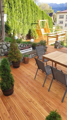 a wooden deck with a wooden table and chairs at Villa Fortuna - Regionalne apartamenty & SPA - Sauna, Grill, Jacuzzi z widokiem na Tatry in Zakopane