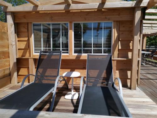 two chairs and a table on a wooden deck at Resort Land & Zee in Scharendijke