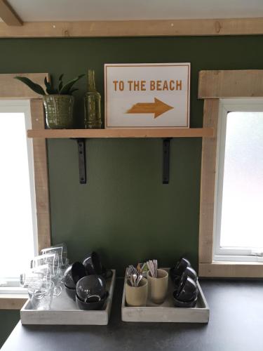 a sign that says to the beach on a wall with two trays at Resort Land & Zee in Scharendijke
