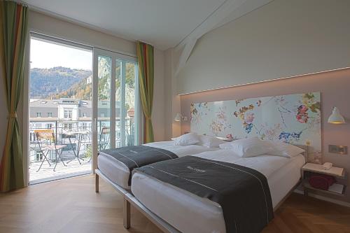 a bedroom with a large bed and a large window at Boutique Hotel Bellevue in Interlaken
