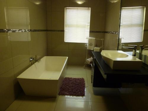 La salle de bains est pourvue d'une baignoire et d'un lavabo. dans l'établissement Springbok Apartments, à Springbok