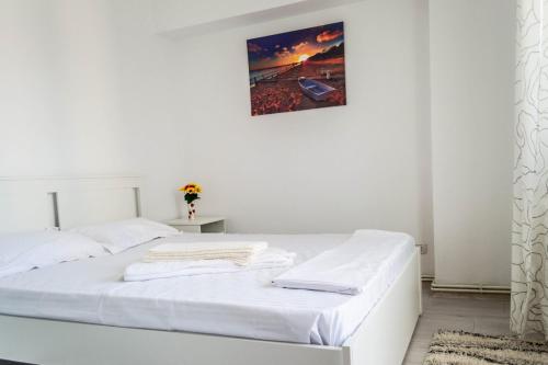 a white bed in a white bedroom with a picture on the wall at Apartament Lara in Constanţa