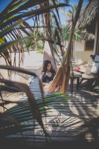 a woman sitting in a hammock on a beach at Un Sueño Cabañas del Pacífico in San Agustinillo