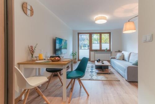 uma sala de estar com uma mesa e um sofá azul em Apartament Magnezja Zakopane em Zakopane