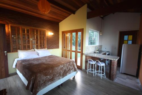 a bedroom with a bed and a kitchen with a counter at Pousada Campestre Sítio da Lua in Camanducaia