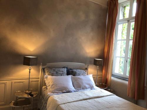 a bedroom with a bed with two lamps and two windows at Château d'en haut in Jenlain