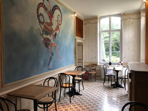 a restaurant with tables and chairs and a painting on the wall at Château d'en haut in Jenlain