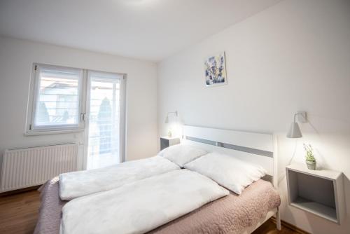 a white bedroom with a bed and a window at Chalet Keszthely in Keszthely