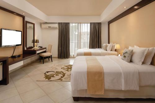 um quarto de hotel com duas camas e uma televisão de ecrã plano em Peninsula Hotel Dar Es Salaam em Dar es Salaam