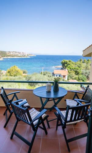 a table and chairs on a balcony with the ocean at The Yellow Houses in Ayios Nikolaos Sithonia