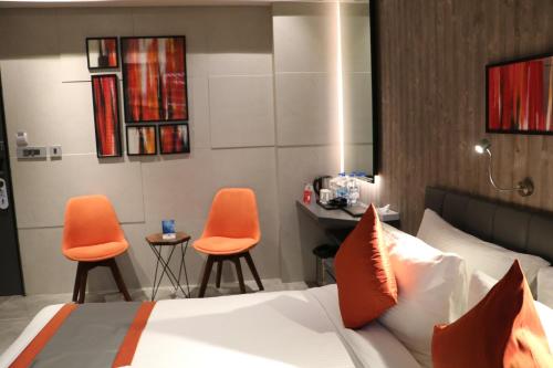 a bedroom with a bed and two orange chairs at The Soni'otel in Hāora