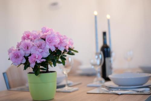 a green vase with pink flowers on a table at Chalet Keszthely in Keszthely